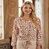 بلوزة بتصميم عصري ونقوش مبهجة، مع عقدة أمامية تمنحها مظهراً مميزاً.