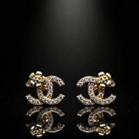 Gemini_Generated_Image_kbe9zdkbe9zdkbe9 حلق بتصميم CC مرصع بفصوص لامعة ولمسة وردة ذهبية أنيقة