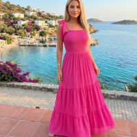 فستان حمالات اللون فوشيا ، طويل، ويصل إلى الكاحلين تقريباً. يتميز بتصميم صيفي خفيف ومريح.